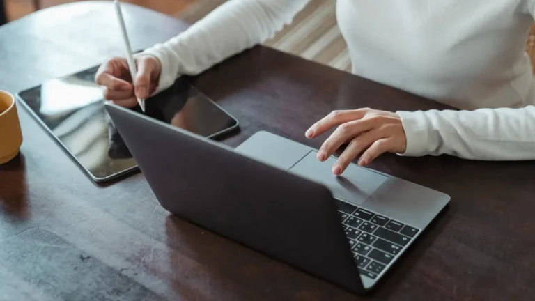 Hand som skriver på dator och en hand som jobbar med en touchboard